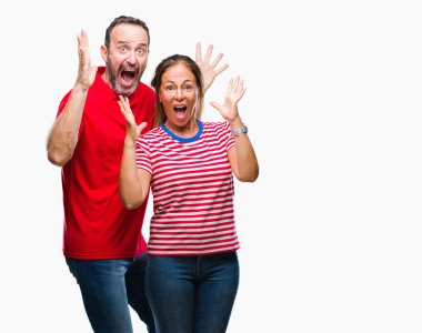 Orta yaş İspanyol çift çılgın kutlama izole arka plan üzerinde seviyorum ve silah ile başarı için yükseltilmiş ve açık gözleri heyecanlı çığlık hayrete düşürdü. Kazanan kavramı