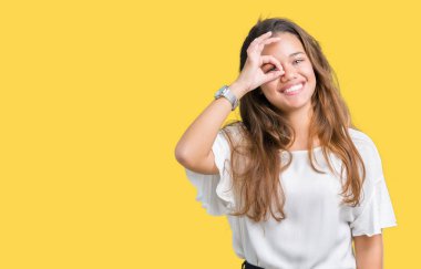 Genç güzel esmer iş kadını gülümseyen, parmakları ile mutlu yüz üzerinden seyir göz el ile ok jest yapıyor izole arka plan üzerinde.