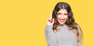 Gösterilen ve kendinden emin ve mutlu gülümseyen bir parmak ile işaret eden oktan yukarı kazak giyen genç güzel kadın çizgili.