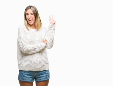 Mutlu yüz zafer işareti yaparken kameraya göz kırpıyor ile gülümseyen izole arka plan üzerinde kış kazak giyen genç güzel kadın. İki numaralı.