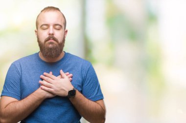 Göğüs kapalı gözler ve yüzünde minnettar jest ile izole arka plan ile gülümseyen üzerinde genç beyaz hipster adam eller. Sağlık kavramı.