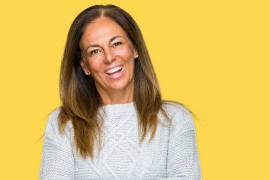 Üzerinde kış kazak giyen güzel orta yaş yetişkin kadın mutlu yüz ile gülümseyerek kameraya seyir silah geçti arka plan izole. Olumlu bir kişi.