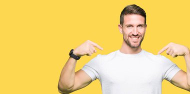 Yakışıklı adam yüzünde gülümseme ile kendinden emin görünüyorsun, kendini gururlu ve mutlu parmakları ile işaret casual beyaz t-shirt giyen.