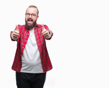 El ile pozitif jest yapıyor onaylama izole arka plan üzerinde gözlük takan Genç beyaz hipster adam başparmak gülümseyen ve başarı için mutlu. Kamera, kazanan jest arıyorsunuz.