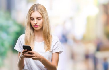 Genç güzel sarışın kadın Smartphone akıllı yüzünde ciddi düşünme emin bir ifade ile izole arka plan üzerinde kullanma