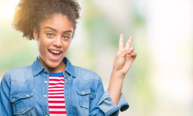 Mutlu yüz zafer işareti yaparken kameraya göz kırpıyor ile gülümseyen izole arka plan üzerinde genç afro Amerikalı kadın. İki numaralı.