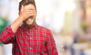 Yakışıklı genç gülümseyen ve gözler için sürpriz kapsayan yüz el ile gülüyor izole arka plan üzerinde. Kör kavramı.