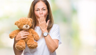 Hata, korku, sessizlik içinde gizli kavramı korkmuş ifade için utanç ile izole arka kapak ağız el ile üzerinden şirin oyuncak ayı peluş tutan orta yaş İspanyol kadın şok