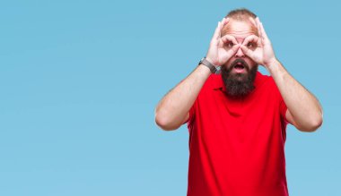 Dilini, parmaklarının arasından baktığını yapışmasını dürbün gibi ok jest yapıyor izole arka plan üzerinde kırmızı gömlek giymiş genç beyaz hipster adam. Deli ifade.