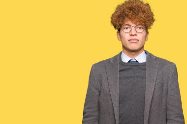 Afro ile genç yakışıklı iş adamı yüzünde ciddi bir ifade ile gözlük giyiyor. Basit ve doğal kamera bakıyor.