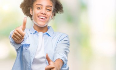 Genç afro Amerikalı kadın el ile pozitif jest yapıyor onaylama izole arka plan üzerinde başparmak gülümseyen ve başarı için mutlu. Kamera, kazanan jest arıyorsunuz.