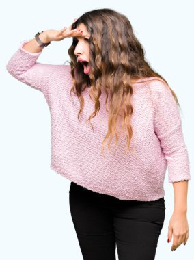 Çok mutlu ve gülümseyen uzakta el ile üzerine kafa seyir pembe kazak giyen genç güzel kadın. Arama kavramı.