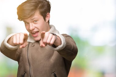 Genç yakışıklı adam giyen kış ceket izole üzerinde arka plan size işaret ve parmaklar, olumlu ve neşeli gülümseyen kamerayla