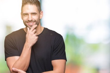 Yakışıklı delikanlı emin çapraz kollar ve çeneme kaldırdı el ile gülümseme ile kameraya bakarak izole arka plan üzerinde. Pozitif düşünce.