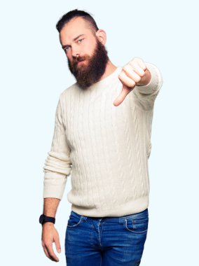 Genç hipster adam kış kazak giyen mutsuz ve kızgın gösteren reddi gösteren ve başparmak aşağı jest ile negatif. Kötü ifade.