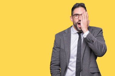 Genç yakışıklı iş adamı el yüz ve sürpriz duygu kendinden emin gülümseme ile tek gözüyle kapsayan izole arka plan üzerinde.