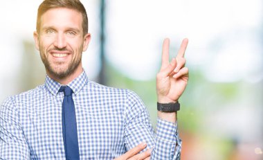 Yakışıklı iş adamı mutlu yüz zafer işareti yaparken kameraya göz kırpıyor ile gülümseyen kravat takıyor. İki numaralı.