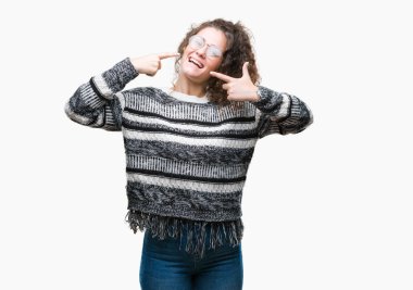 Güzel esmer kıvırcık saçlı Genç kız kendinden emin gösterilen ve işaret parmakları diş ve ağız ile gülümseyen izole arka plan üzerinde gözlük takıyorum. Sağlık kavramı.