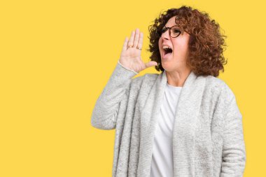 Ceket ve gözlük bağırarak ve ağzı üzerinde el ile yan için çığlık izole arka plan üzerinde giyen güzel orta ager üst düzey kadın. İletişim kavramı.