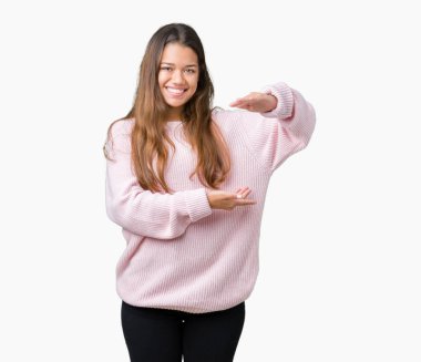 İzole arka plan eller eller büyük gösterilen ve büyük boy işareti, ölçü birimi sembolü ile üzerinde pembe kış kazak giyen genç güzel esmer kadın. Kameraya bakarak gülümsüyordu. Ölçüm kavramı.