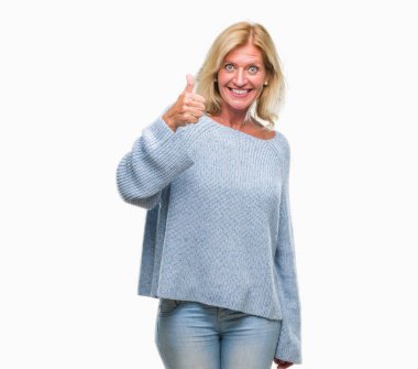 Orta yaş sarışın kadın hareketi el ile mutlu yaşasın yapıyor izole arka plan üzerinde kış kazak giyiyor. Kameraya bakarak başarı gösteren ile ifade onaylama.