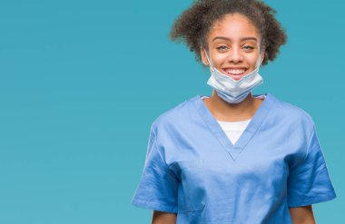 Genç afro Amerikalı doktor kadın yüzünde mutlu ve güzel bir gülümseme ile izole arka plan yüzünden. Şanslı kişi.