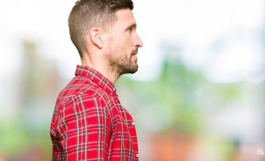 Yakışıklı erkek tarafına, seyir sıradan gömlek giymiş dinlenmek doğal yüz emin gülümseme ile pozuyla profil.