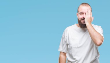 Üzerinde rahat t-shirt giyen genç beyaz hipster adam arka plan kapsayan bir göz yüz ve sürpriz duygu kendinden emin gülümseme ile el ile izole.