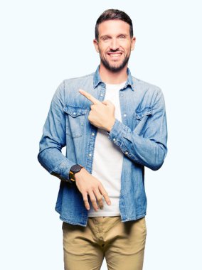 Yakışıklı adam mavi gözleri ve denim ceket neşeli bir gülümseme ile el ve parmak kadar yan yüzünde mutlu ve doğal ifade ile işaret yüz sakal