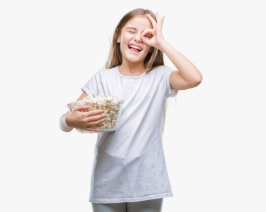 Yeme patlamış mısır snack izole arka plan ile mutlu yüz el parmaklarının arasından seyir göz üzerinde ok işaretiyle yapıyor gülümseyen genç güzel kız