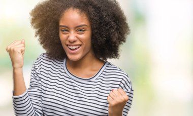 Gülümseyen ve başarı için çığlık genç afro Amerikan kadın izole arka plan çok mutlu ve heyecanlı kaldırdı, silah ile kazanan jest yapıyor. Kutlama kavramı.