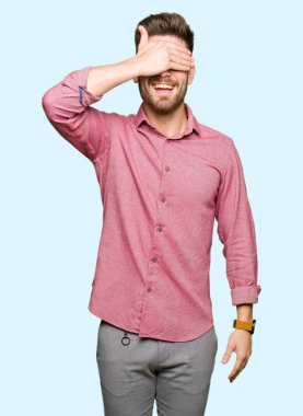 Genç yakışıklı iş casual adam gülümsüyor ve gözleri için sürpriz kapsayan yüz el ile gülüyor. Kör kavramı.