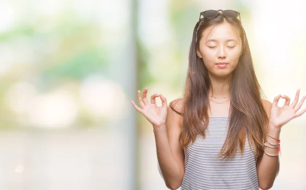 年轻的亚洲妇女戴着太阳镜在孤立的背景下放松和微笑闭上眼睛做冥想手势用手指 瑜伽理念 — 图库照片