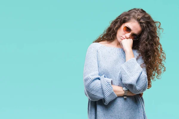 Güzel esmer kıvırcık saçlı Genç kız izole arka plan düşünme seyir güneş gözlüğü takıyor yorgun ve sıkılmış çapraz silah depresyon sorunları ile.