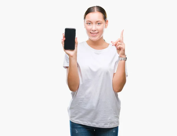 年轻美丽的高加索妇女显示智能手机屏幕在孤立的背景惊讶的想法或问题用快乐的脸指指点点 — 图库照片
