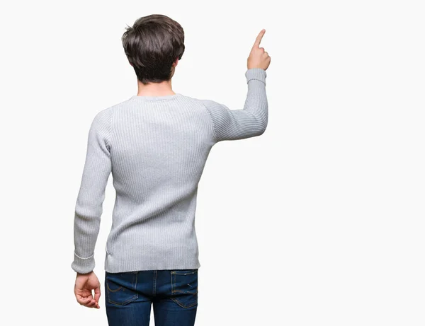 年轻英俊的男人穿着冬天的毛衣在孤立的背景摆在后面用手指手指着后面 — 图库照片