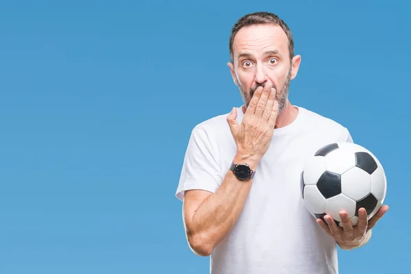 Middle age hoary senior man holding soccer football ball over isolated background cover mouth with hand shocked with shame for mistake, expression of fear, scared in silence, secret concept
