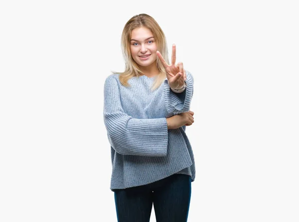 勝利のサインを行うカメラでウィンクしている幸せそうな顔を浮かべて隔離された背景に冬のセーターを着た若い白人女性 — ストック写真