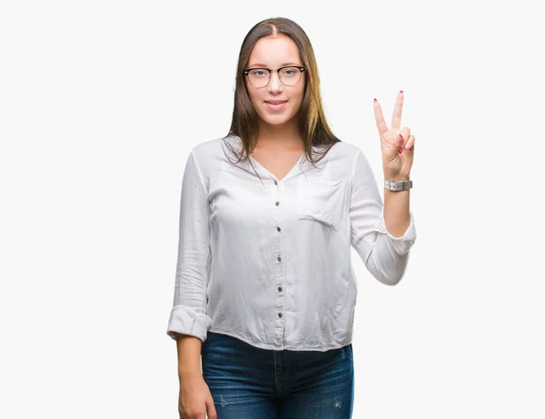 年轻的高加索美丽的女商人戴着眼镜在孤立的背景显示和手指第二 同时微笑着自信和快乐 — 图库照片