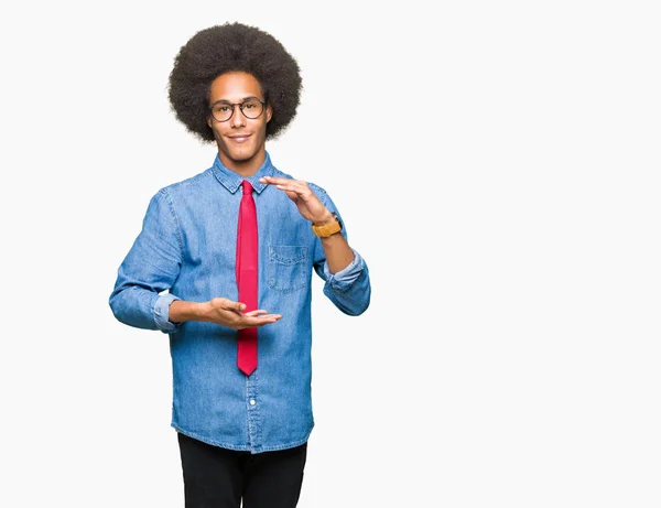 年轻的非洲裔美国商人戴着非洲头发戴着眼镜 用红色领带做手势 手上有大尺寸的标志 尺寸符号 看着镜头微笑 测量概念 — 图库照片