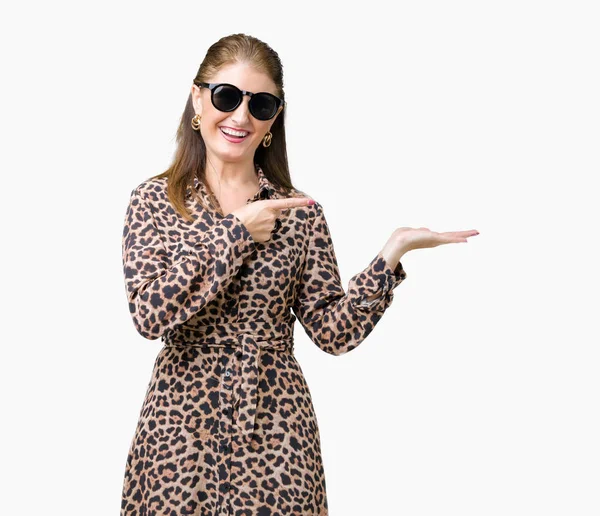 中年成熟した豊かな女性の身に着けているサングラスとヒョウの驚くし 手とを提示 指で指している間カメラに笑顔孤立の背景にドレスします — ストック写真