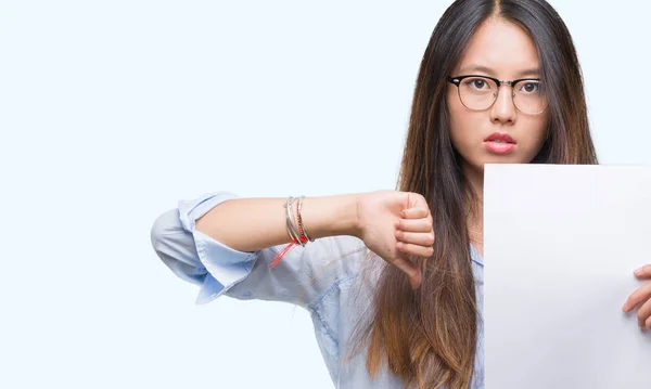 年轻的亚洲妇女拿着空白的纸在孤立的背景与愤怒的面孔 消极标志显示不喜欢与拇指下来 拒绝概念 — 图库照片