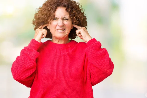美丽的中间年龄的资深妇女红色冬天毛衣在被隔绝的背景覆盖耳朵用手指与愤怒的表示为大声的音乐的噪声 聋哑人的概念 — 图库照片