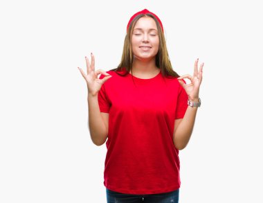 İzole arka plan üzerinde beyaz genç güzel kadın dinlenmek ve gülümseyen gözlerle kapalı parmak jestle meditasyon yapıyor. Yoga kavramı.