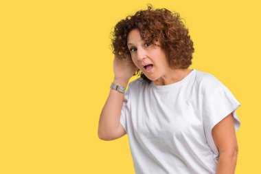Bir işitme söylenti ya da dedikodu için dinleme kulak üzerinde el ile gülümseyen izole arka plan üzerinde beyaz t-shirt giyen güzel orta ager kadın kıdemli. Sağırlık kavramı.