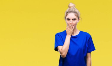 İzole arka plan üzerinde mavi t-shirt giyen genç güzel sarışın ve mavi gözlü kadın esneme yorgun kapsayan ağız el ile sıkılmış. Restless ve uyku hali.