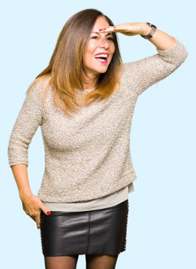 Moda kazak çok mutlu ve gülümseyen uzakta el ile üzerine kafa seyir giyen güzel orta yaş kadın. Arama kavramı.