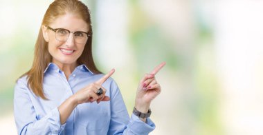 Güzel orta yaş olgun iş kadını gülümseyen ve iki elleri ve parmakları ile tarafına işaret kamera bakarak izole arka plan üzerinde gözlük.