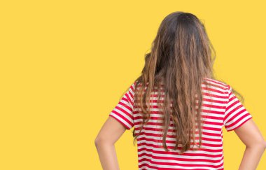 İzole arka plan ayakta geriye doğru uzakta silah ile vücut üzerinde seyir üzerinde tişört giyen genç güzel esmer kadın çizgili