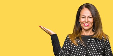 Neşeli sunulması ve kameraya bakarak avucunun ile işaret gülümseyen moda ceket giyen güzel orta yaş kadın.